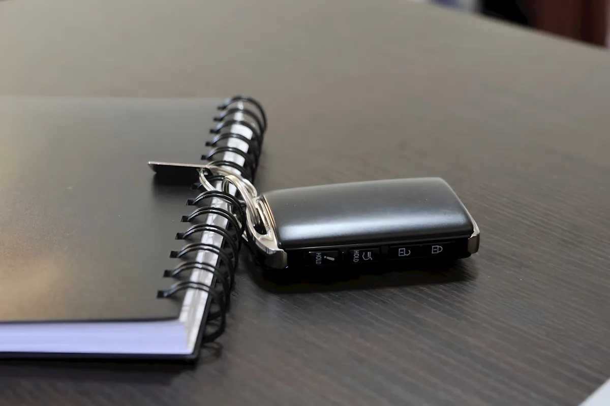 Car key fob resting on a notebook of auto insurance notes